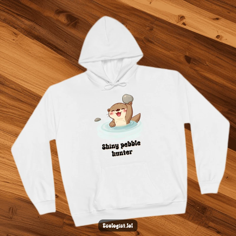 Funny, joyful otter swimming in a clear stream, proudly displaying a shiny clean pebble, featured on a soft hoodie.
